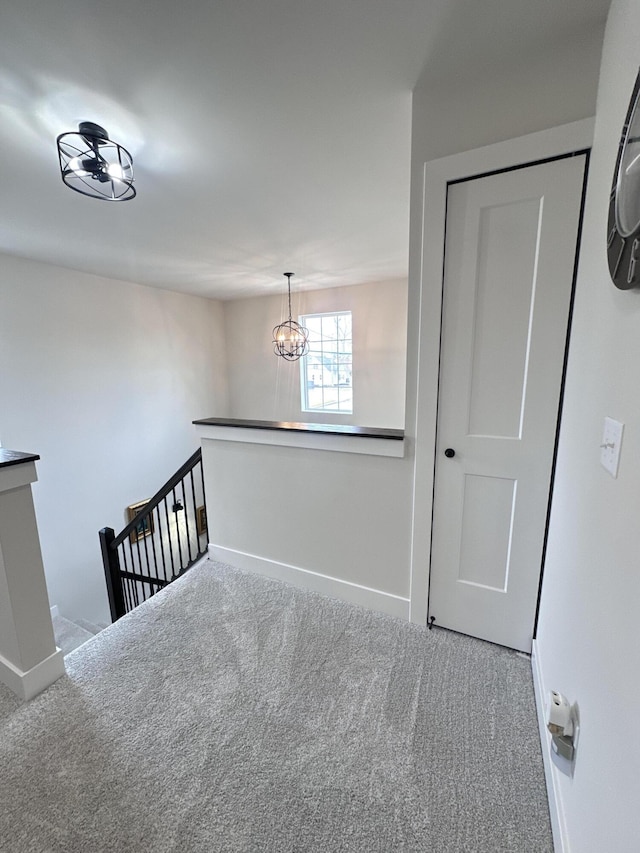 interior space with an inviting chandelier, carpet, baseboards, and an upstairs landing