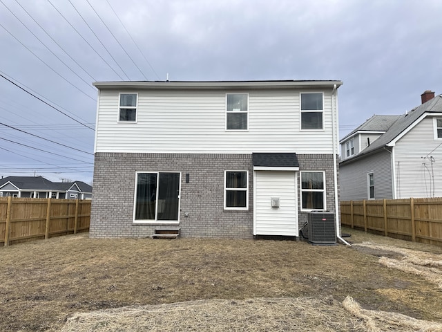 back of property featuring central AC, brick siding, and a fenced backyard