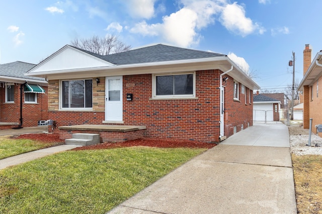 bungalow-style house with a detached garage, roof with shingles, an outdoor structure, a front lawn, and brick siding