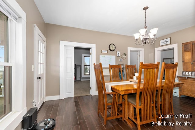 dining space with a notable chandelier, baseboards, and dark wood-type flooring