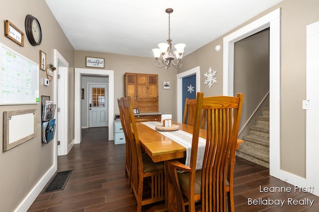 dining space with a notable chandelier, wood finish floors, visible vents, baseboards, and stairway