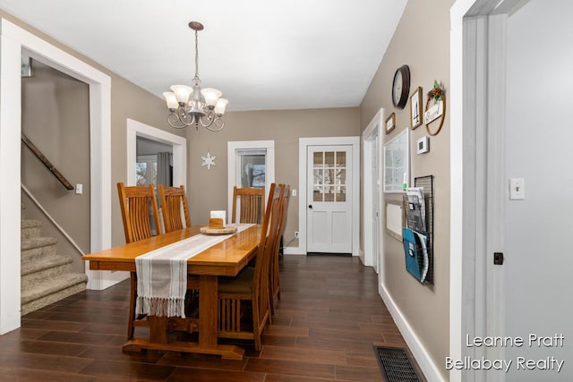 dining room featuring a notable chandelier, visible vents, baseboards, stairs, and dark wood finished floors