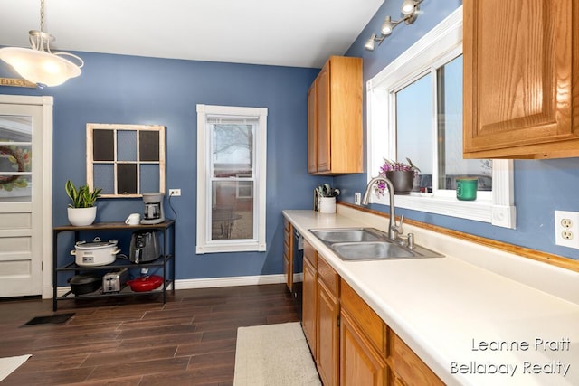 kitchen with dark wood-style flooring, a sink, baseboards, light countertops, and hanging light fixtures