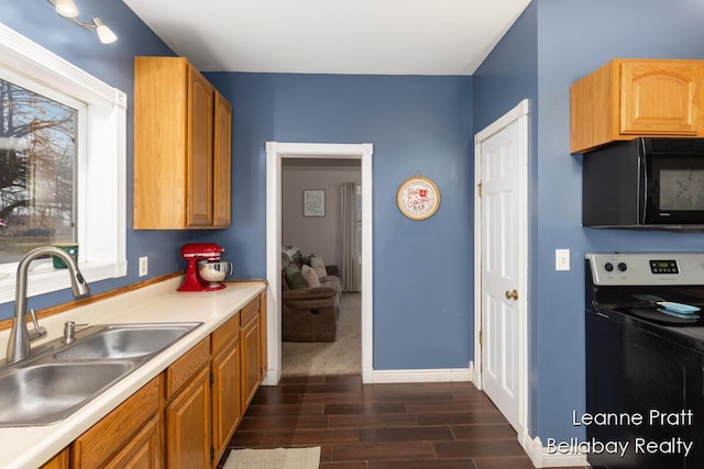 kitchen featuring black microwave, dark wood-type flooring, range with electric cooktop, a sink, and light countertops