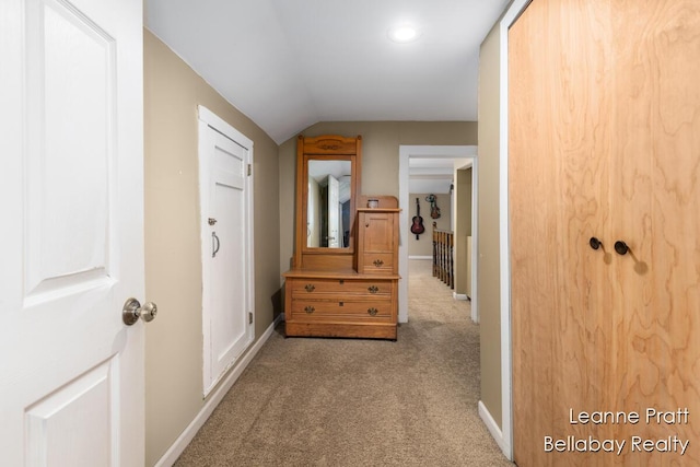 corridor with carpet floors, baseboards, and vaulted ceiling