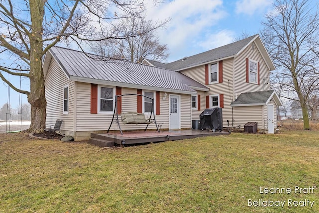 view of front of property featuring metal roof, a wooden deck, an outbuilding, and a front yard