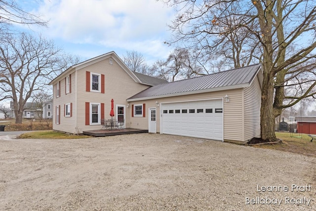 view of front of house with driveway, an attached garage, metal roof, and a wooden deck