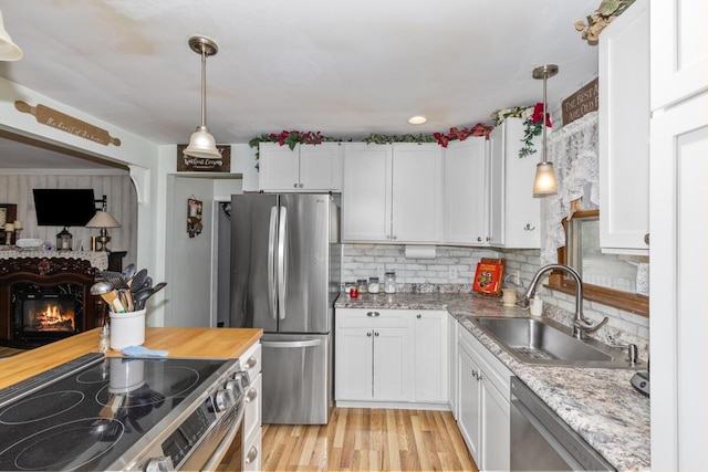 kitchen with light wood finished floors, white cabinetry, appliances with stainless steel finishes, and a sink