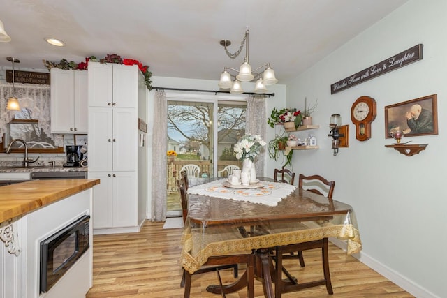 dining room featuring an inviting chandelier, light wood-style flooring, baseboards, and recessed lighting