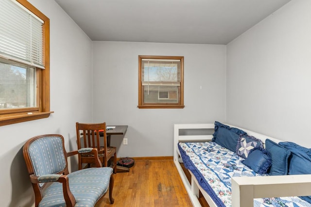 bedroom with multiple windows, baseboards, and wood finished floors