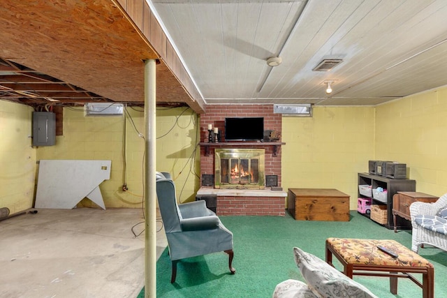 finished basement with electric panel, visible vents, and a fireplace