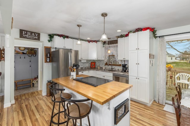 kitchen featuring white cabinets, butcher block counters, stainless steel appliances, and light wood-style flooring