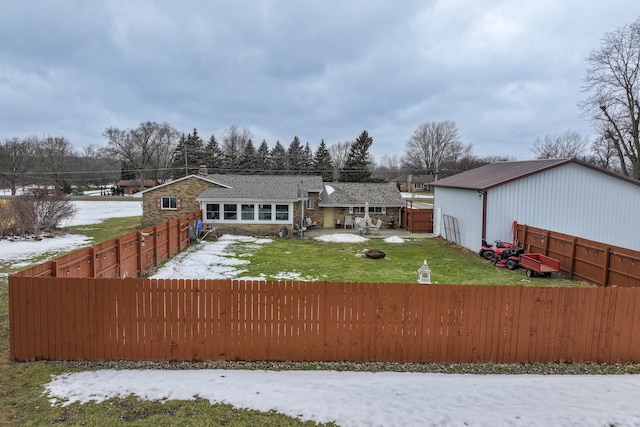 view of front facade with stone siding, a fenced backyard, and a lawn