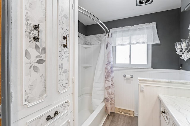 full bathroom with a wainscoted wall, vanity, wood finished floors, and shower / bath combo with shower curtain