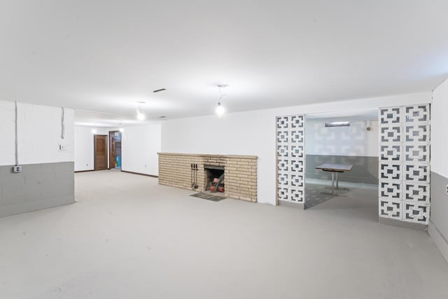 finished basement featuring concrete block wall and a brick fireplace