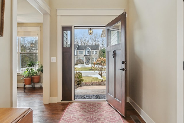 foyer entrance with visible vents, dark wood finished floors, and baseboards