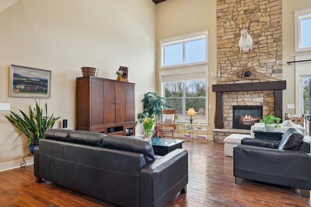 living area featuring a high ceiling, hardwood / wood-style floors, and a stone fireplace