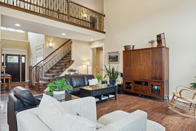 living room featuring baseboards, stairs, a high ceiling, and dark wood-style flooring