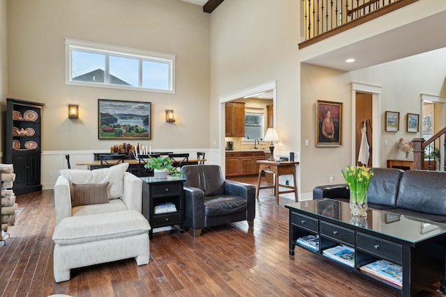 living room with dark wood-style floors, a towering ceiling, and stairs