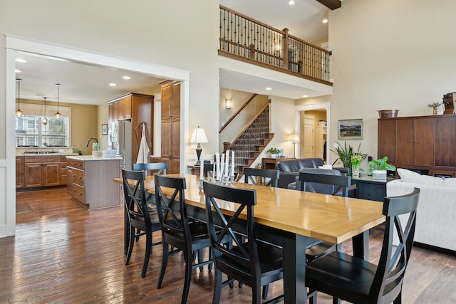 dining room with dark wood-style floors, stairs, a high ceiling, and recessed lighting