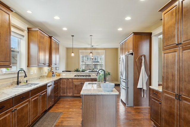 kitchen featuring dark wood-style floors, appliances with stainless steel finishes, light stone counters, and a sink