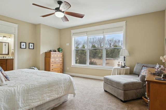 bedroom with ensuite bath, baseboards, a ceiling fan, and light colored carpet