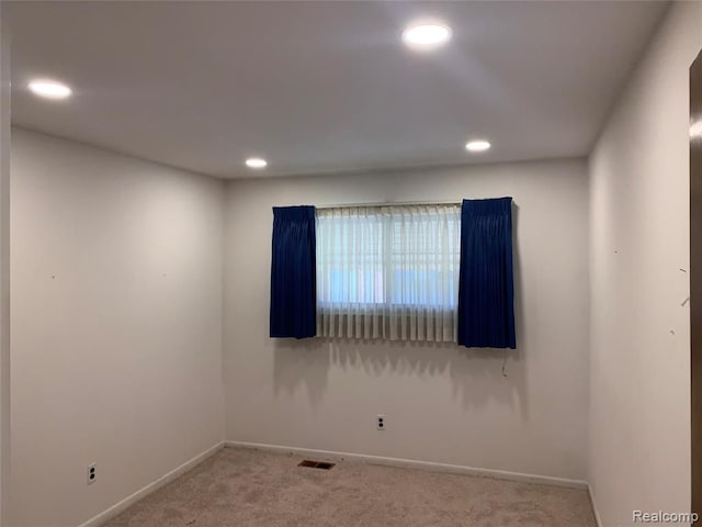 carpeted spare room featuring baseboards, visible vents, and recessed lighting