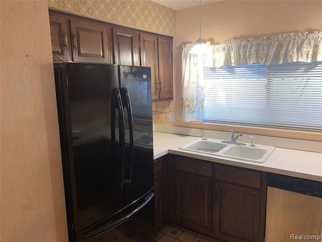 kitchen with wallpapered walls, dishwasher, freestanding refrigerator, light countertops, and a sink