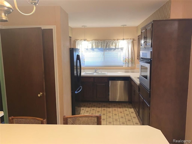 kitchen with light floors, light countertops, hanging light fixtures, appliances with stainless steel finishes, and a sink