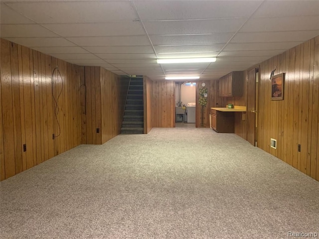 finished below grade area featuring separate washer and dryer, stairway, carpet flooring, and wooden walls