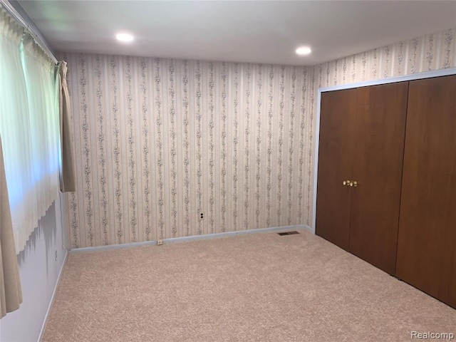 empty room featuring baseboards, carpet floors, and wallpapered walls