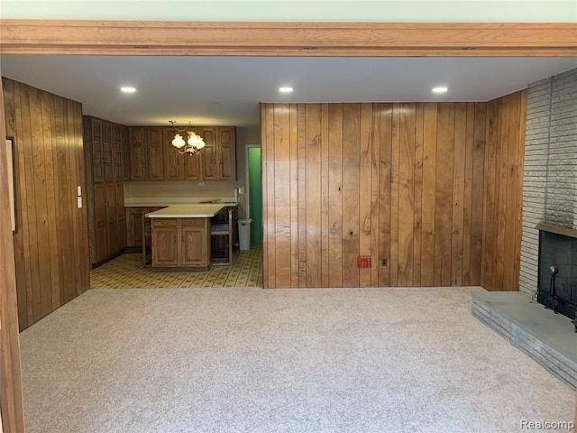 interior space with light carpet, brown cabinetry, light countertops, wood walls, and a fireplace