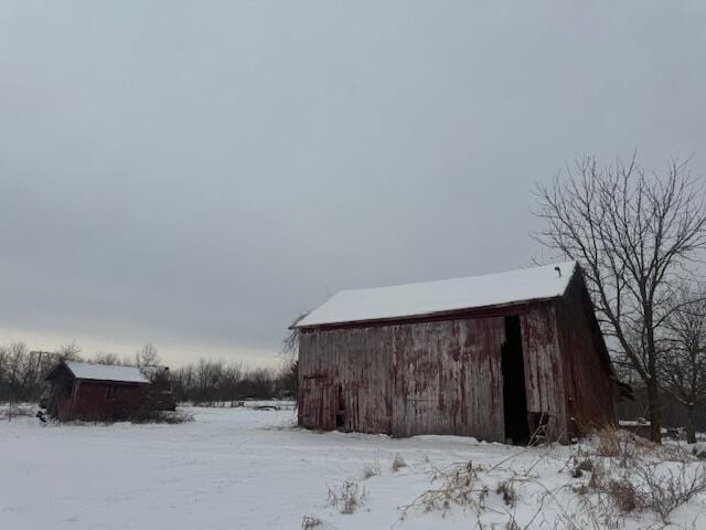 snow covered structure with an outbuilding