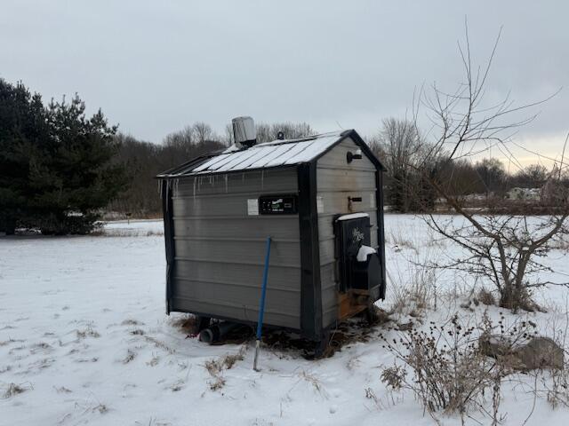 snow covered structure featuring a storage shed and an outdoor structure