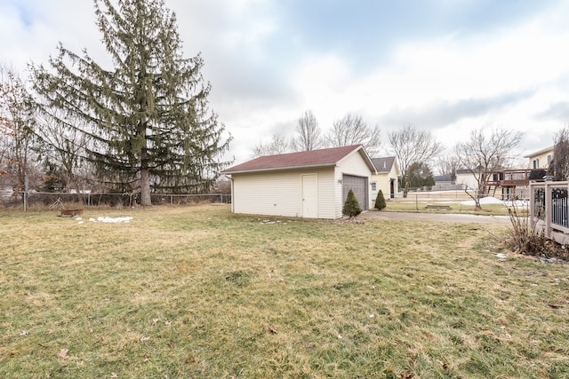 view of yard featuring fence, a detached garage, and an outdoor structure