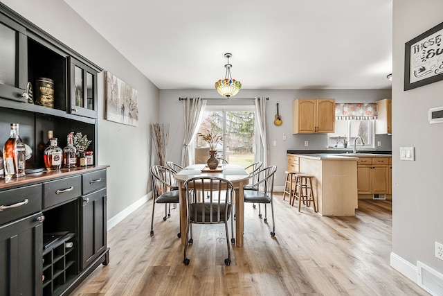 dining area featuring light wood finished floors, visible vents, and baseboards