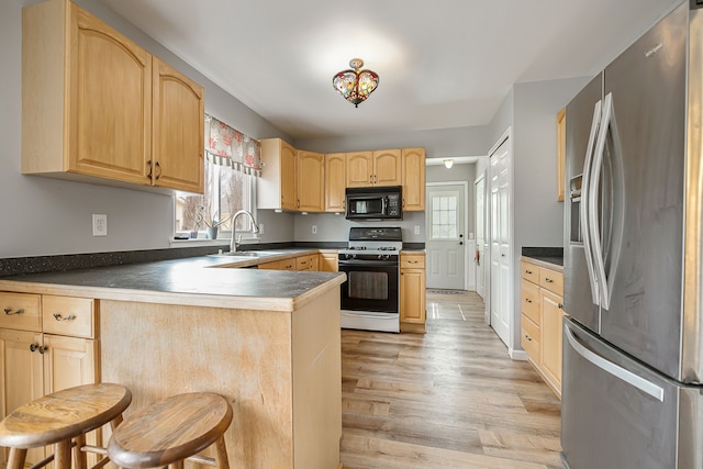 kitchen with gas range oven, light brown cabinetry, a sink, black microwave, and stainless steel fridge with ice dispenser