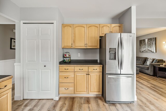 kitchen featuring dark countertops, light wood-style flooring, open floor plan, light brown cabinetry, and stainless steel refrigerator with ice dispenser