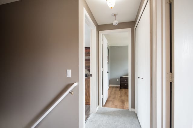 corridor featuring light carpet and an upstairs landing