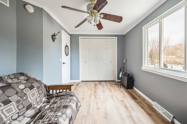 living area featuring baseboards, light wood finished floors, visible vents, and crown molding