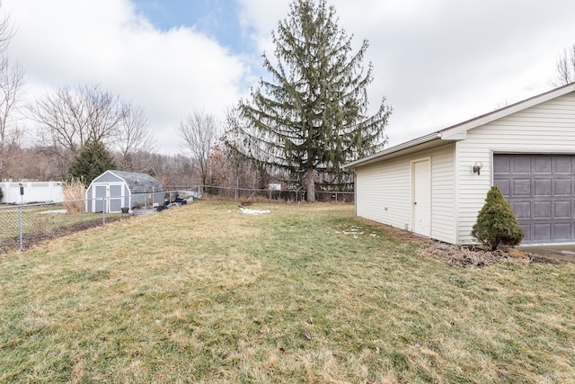 view of yard with a garage, a fenced backyard, and an outbuilding