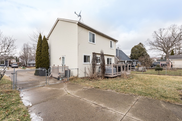 view of side of home with a gate, fence, a lawn, and a wooden deck