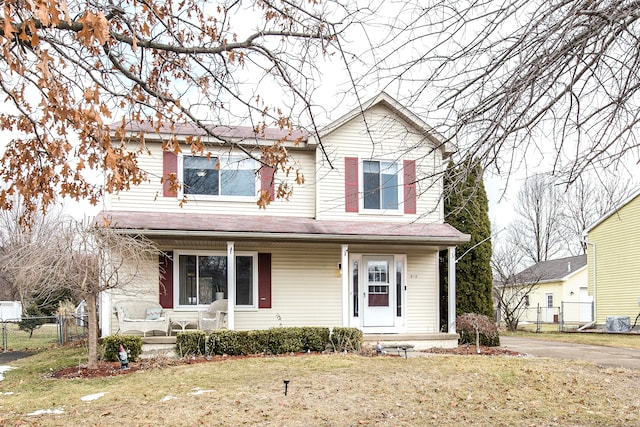 traditional-style house with a front yard, covered porch, and fence