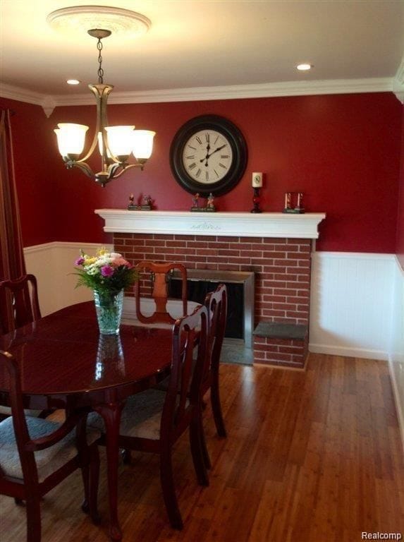 dining area with a wainscoted wall, ornamental molding, and wood finished floors