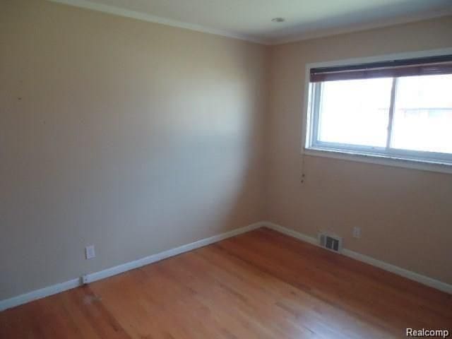 spare room with light wood-style floors, visible vents, and baseboards