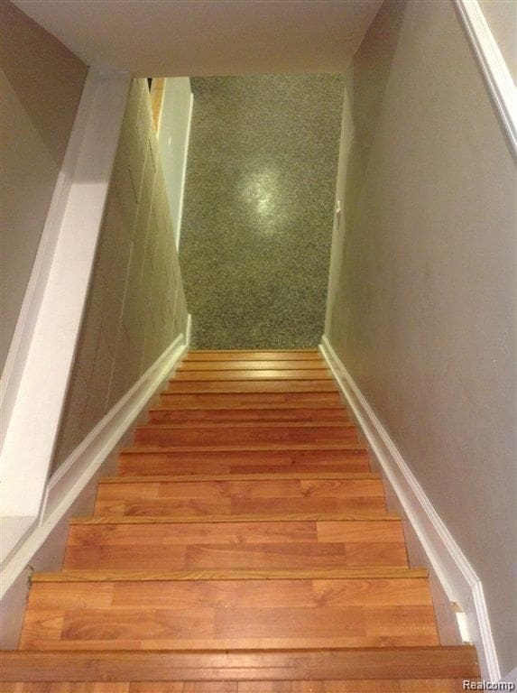 staircase featuring baseboards and wood finished floors