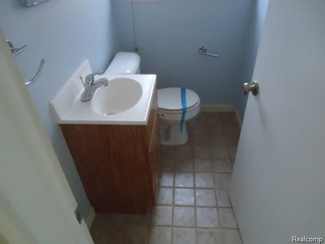 bathroom with baseboards, vanity, and toilet