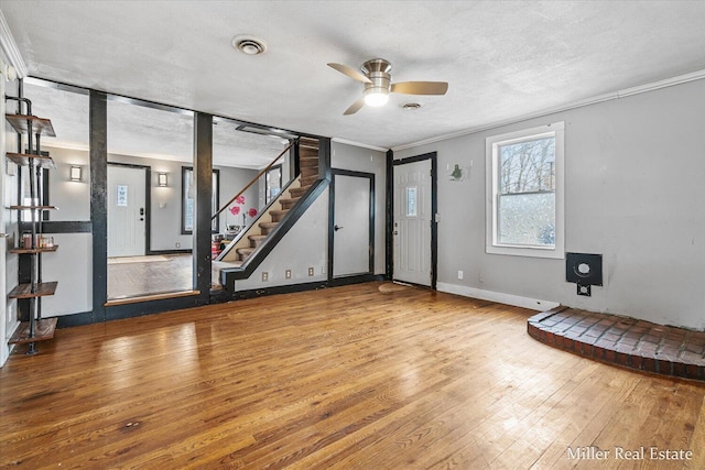 exercise area featuring a textured ceiling, hardwood / wood-style flooring, visible vents, baseboards, and crown molding