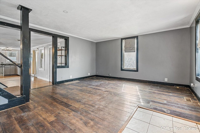 unfurnished room with visible vents, ornamental molding, a textured ceiling, baseboards, and hardwood / wood-style flooring