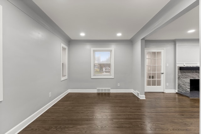 unfurnished living room with recessed lighting, a fireplace, visible vents, baseboards, and dark wood-style floors